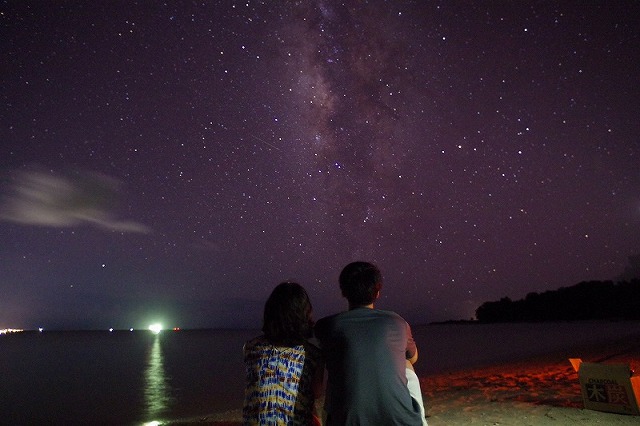 砂浜で星を見るカップル